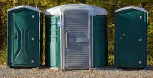 ada porta potty in line with three regular portable toilets